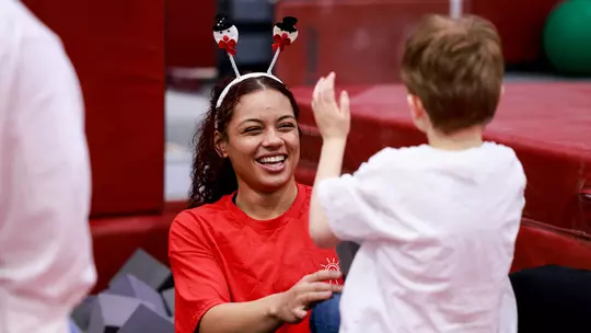 Makarri Doggette playing with a young child while wearing a silly headband