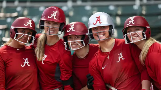 Softball players posing together in batting helmets