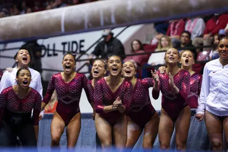 The Alabama Gymnastics team cheering on a teammate who is on the balance beam