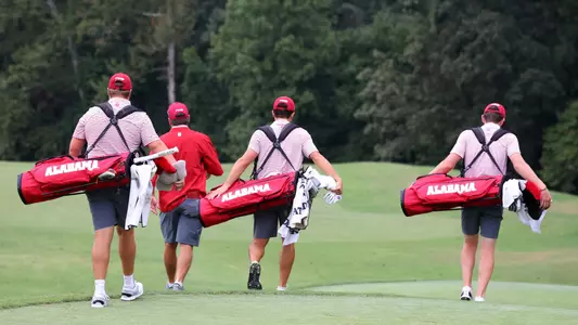 Alabama men's golfers walk down a fairway with coach Jay Seawell