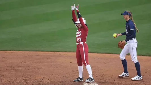 Alabama softball player Faith Hensley throw up a W on the field.