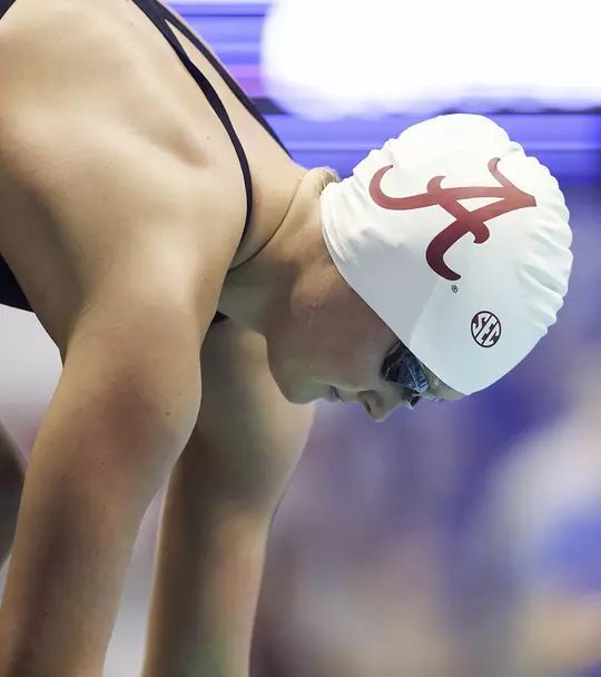 Kensey McMahon bent over in a starting position wearing a swim cap