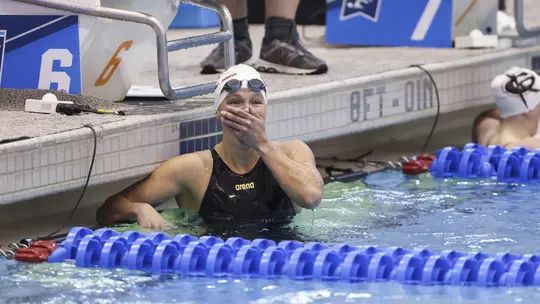 Kensey McMahon at the edge of the pool with her hand over her mouth in shock