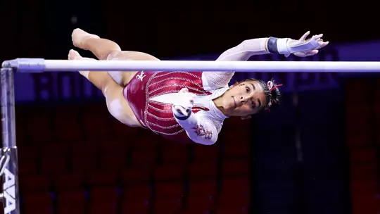 Luisa Blanco in the air reaching for the uneven bars