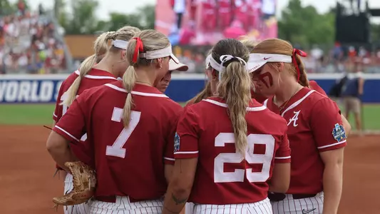 Alabama softball players huddle in between innings vs. Tennessee at the WCWS (June 1, 2023)