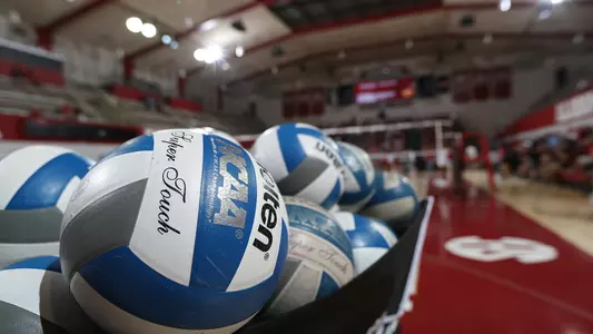 Volleyballs in a bin with the court in the background
