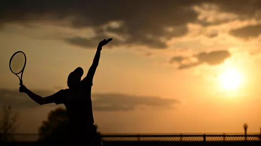 Athlete playing tennis shadowed against a yellow sunset