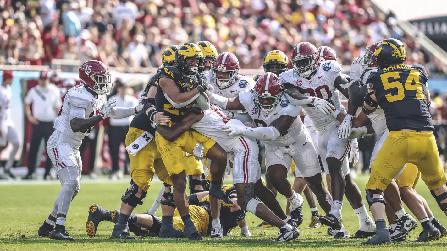 Alabama players tackling the opposing Michigan team