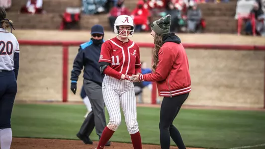 Alabama softball player Larissa Preuitt stands on first with Coach Braud.