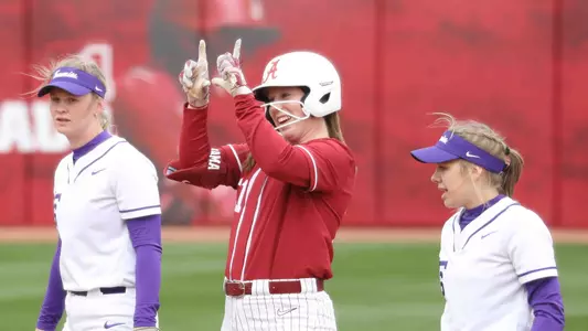 Alabama softball player Kenleigh Cahalan celebrates getting on base, throwing up the Bama U sign with her hands.