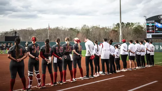 Alabama softball players and staff stand on the foul line during the national anthem vs. Georgia (March 15, 2024)