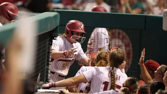 Alabama softball player Kenleigh Cahalan (31) celebrating in the dugout with her teammates after scoring a run against Texas A&M.