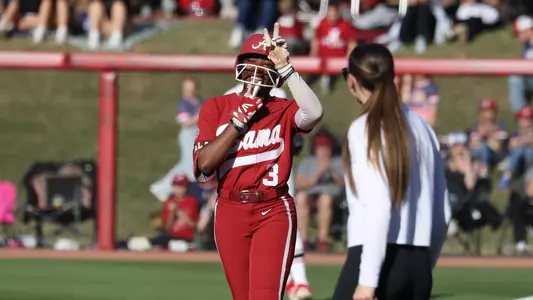 Alabama softball plater Kristen White (3) on first with Coach Kayla Braud after hitting a single.