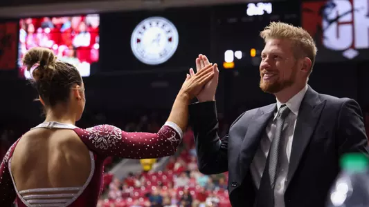 Assistant Coach Justin Spring congratulating UA gymnast during home meet
