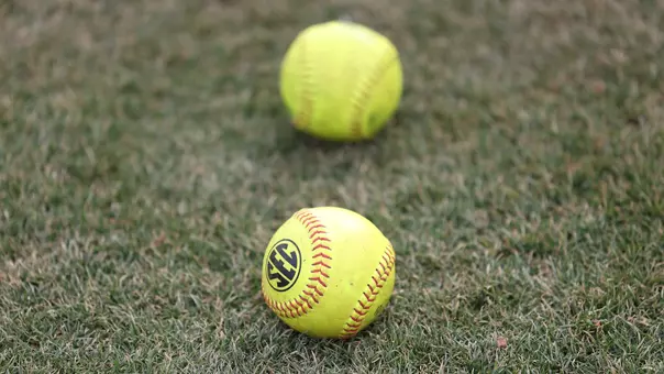 Two softballs in the grass