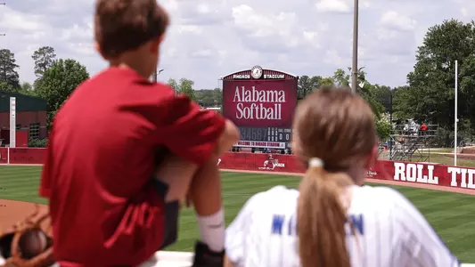 Two young fans look onto the field with the scoreboard in the background