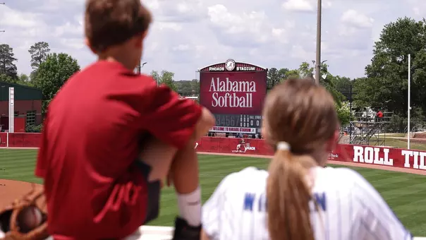 Two young fans look onto the field with the scoreboard in the background