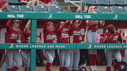 Alabama softball players cheering from the dugout