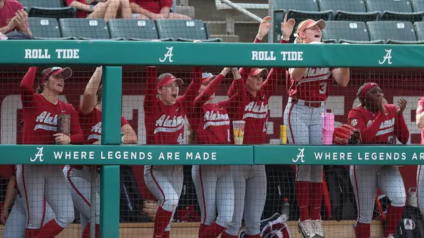 Alabama softball players cheering from the dugout