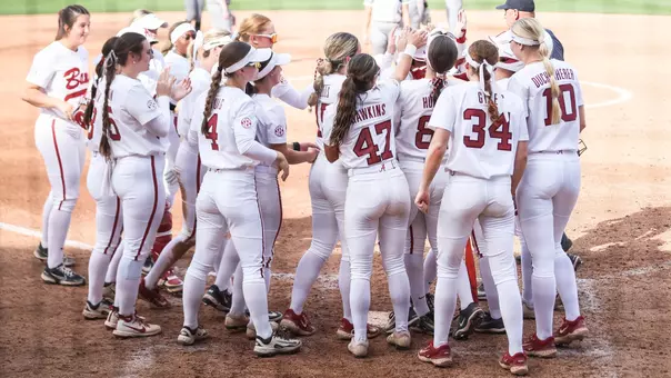 Alabama softball players celebrate at home plate after a home run