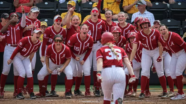 Alabama softball players wait at home plate to celebrate an Ambrey Taylor (36) home run