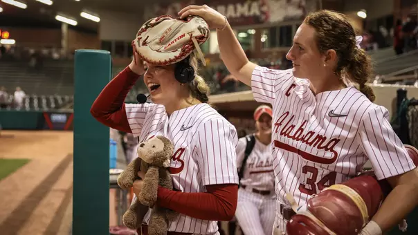 Marlie Giles (34) puts a glove on Brooke Wells' (15) head during a postgame interview
