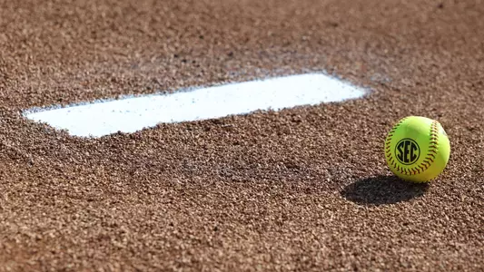 A softball laying in the pitcher's circle