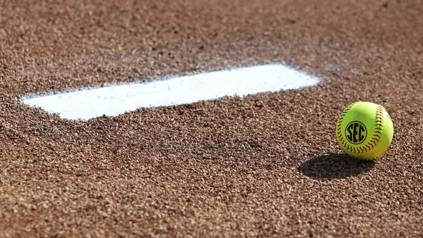 A softball laying in the pitcher's circle