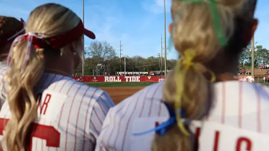 Outfield fence at Rhoads Stadium in the background with two players out of focus in the foreground