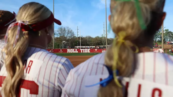 Outfield fence at Rhoads Stadium in the background with two players out of focus in the foreground