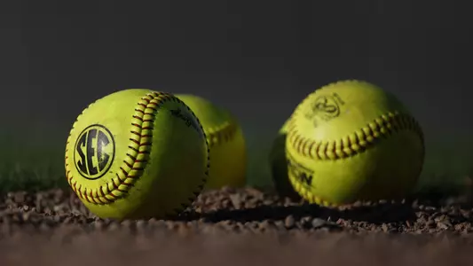 Three softballs laying in the dirt