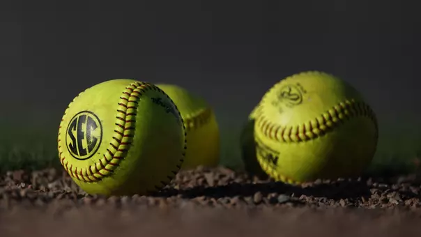Three softballs laying in the dirt