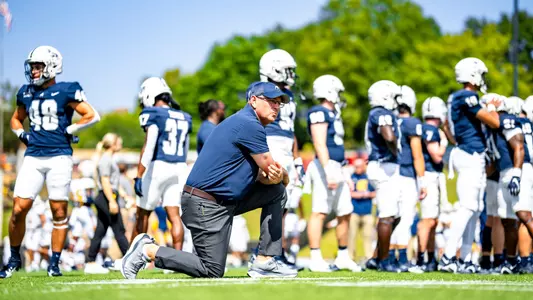 Head Coach Chris Hatcher kneeling during 2024 season