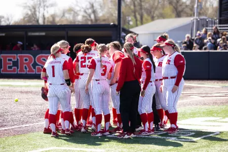 The Rutgers softball team huddles along the third-base line prior to the start of the series finale with Nebraska at the Rutgers Softball Complex