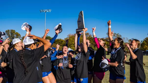 Soccer players celebrate a championship holding a Summit League trophy
