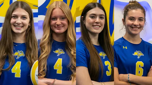 Four volleyball players pose in blue uniforms