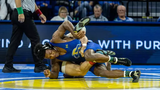 Marcus Espinoza-Owens works to score a takedown on his opponents legs during his match against Augustana.
