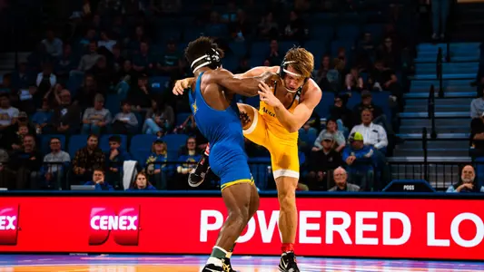 A wrestler grabs the leg of his opponent, trying to obtain a takedown.