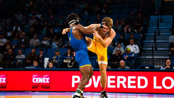 A wrestler grabs the leg of his opponent, trying to obtain a takedown.