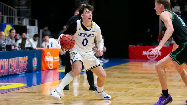 Trey Buchanan dribbles a basketball against a defender