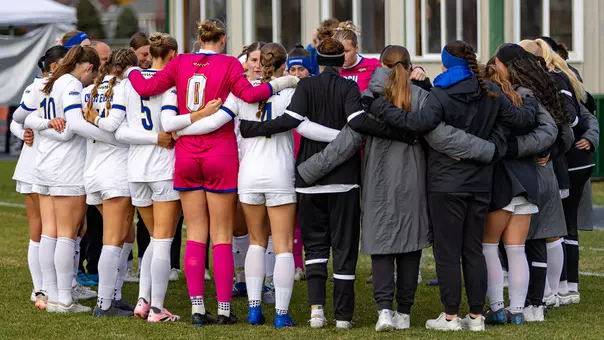 Soccer players huddle before a game at Fishback Soccer Park