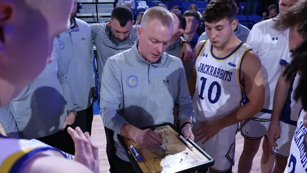 Bryan Petersen writes on a board at a basketball game