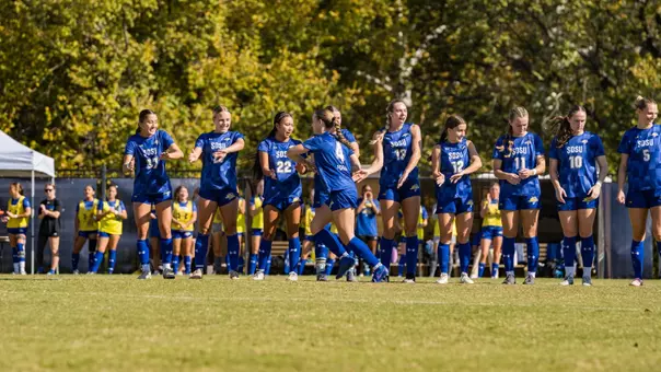 Lauren Eckerle high fives her teammates as starting lineups are announced on a soccer field