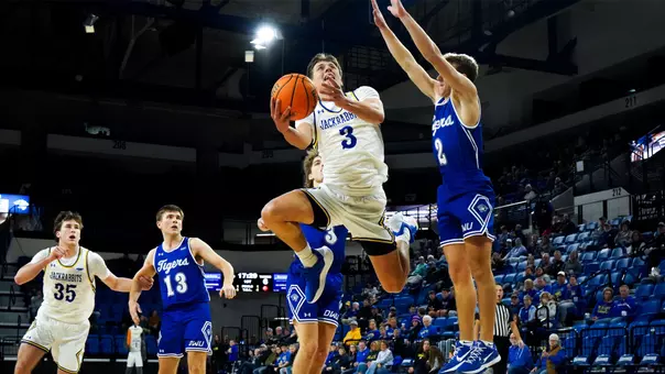 A men's basketball player jumps in the air attempting to shoot a ball