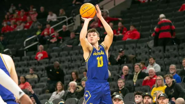 A men's basketball player shoots a basketball from above his head