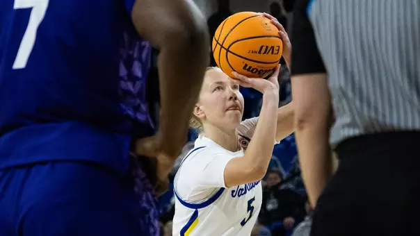 A women's basketball player in a white uniform attempts a free throw