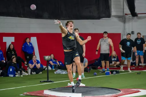 Male thrower releases a shot put during a track and field competition
