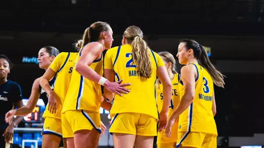 Members of the South Dakota State women's basketball team huddle on the court during a game