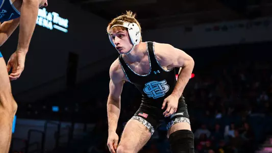 A wrestler in a black singlet goes for a takedown in a match with Air Force.