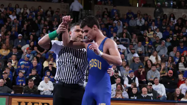 A wrestler, Julian Tagg, has his hand raised by the referee after a win